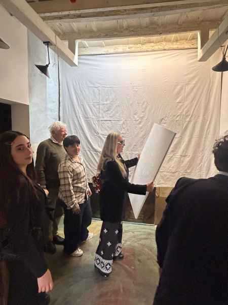 Veronica sta collocando il dipinto  con i suoi allievi e si vede alle sue spalle Andrea Bottai fondatore di Pian dè Giullari